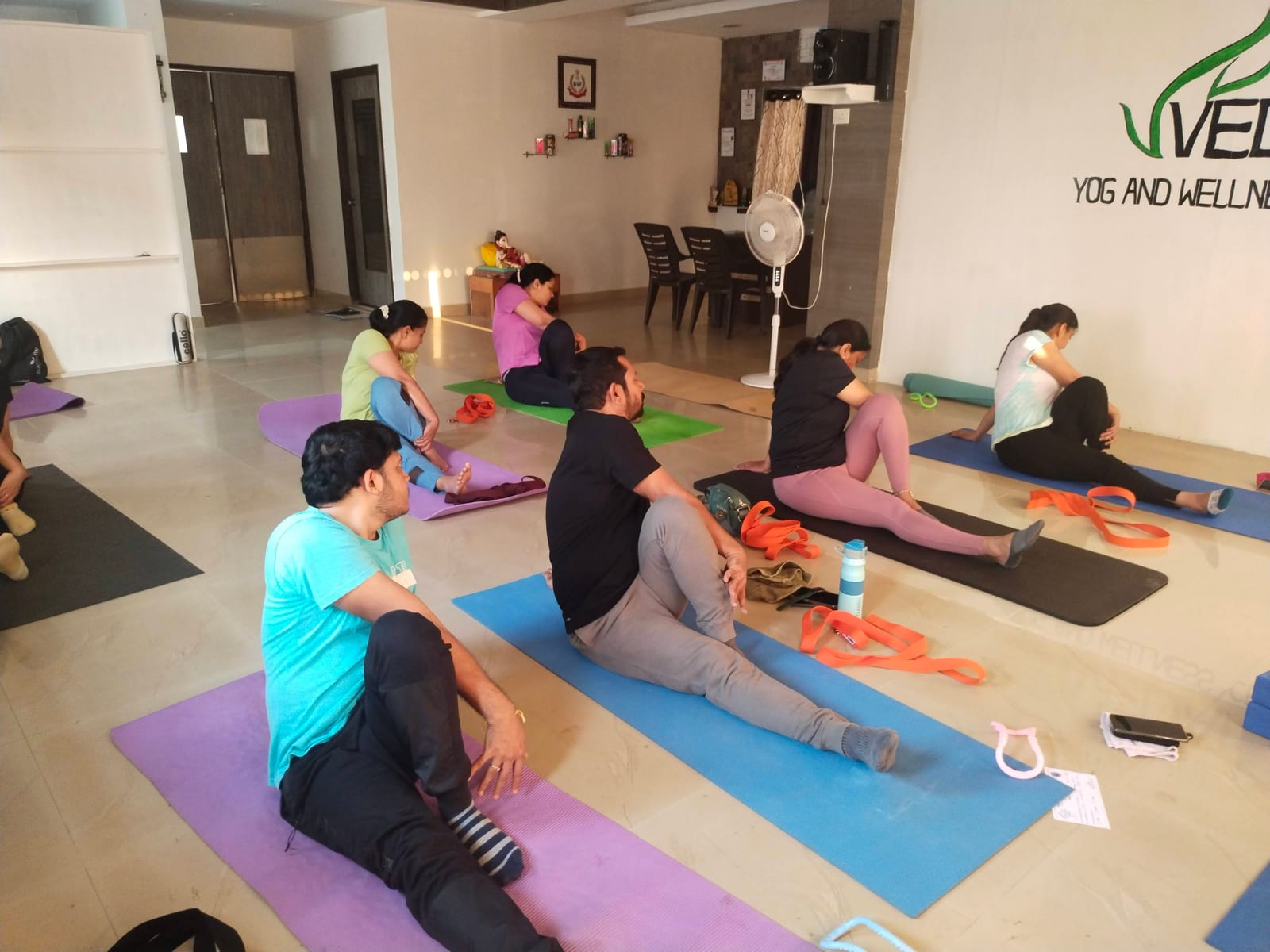 Group of students in seated forward-bend using yoga straps for support