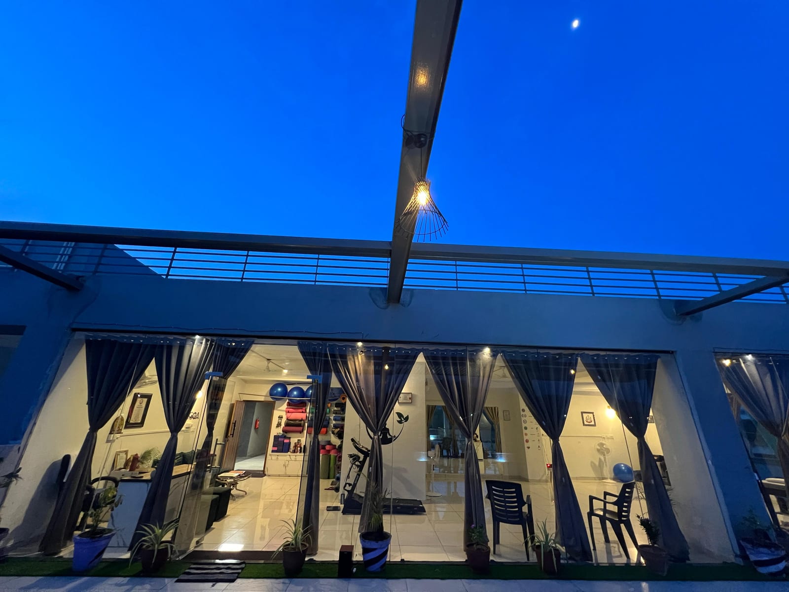 Vedang Yog Studio exterior at dusk, glass storefront lit from within